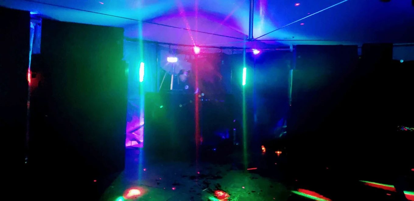Colorful laser lights cutting through a dark tent late at night