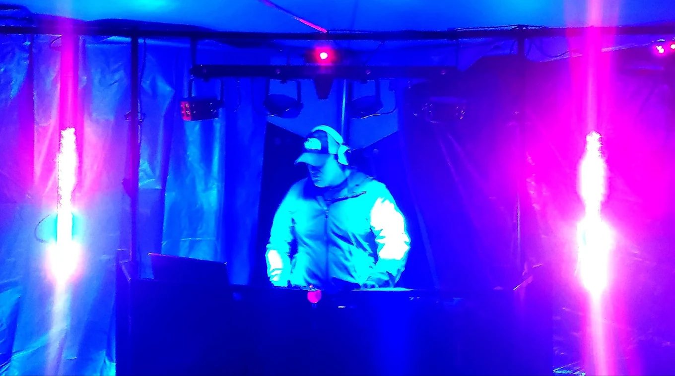 Mike DJing under a tent at an evening event